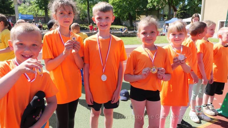 grupa dzieci w pomarańczowych koszulkach, z medalami